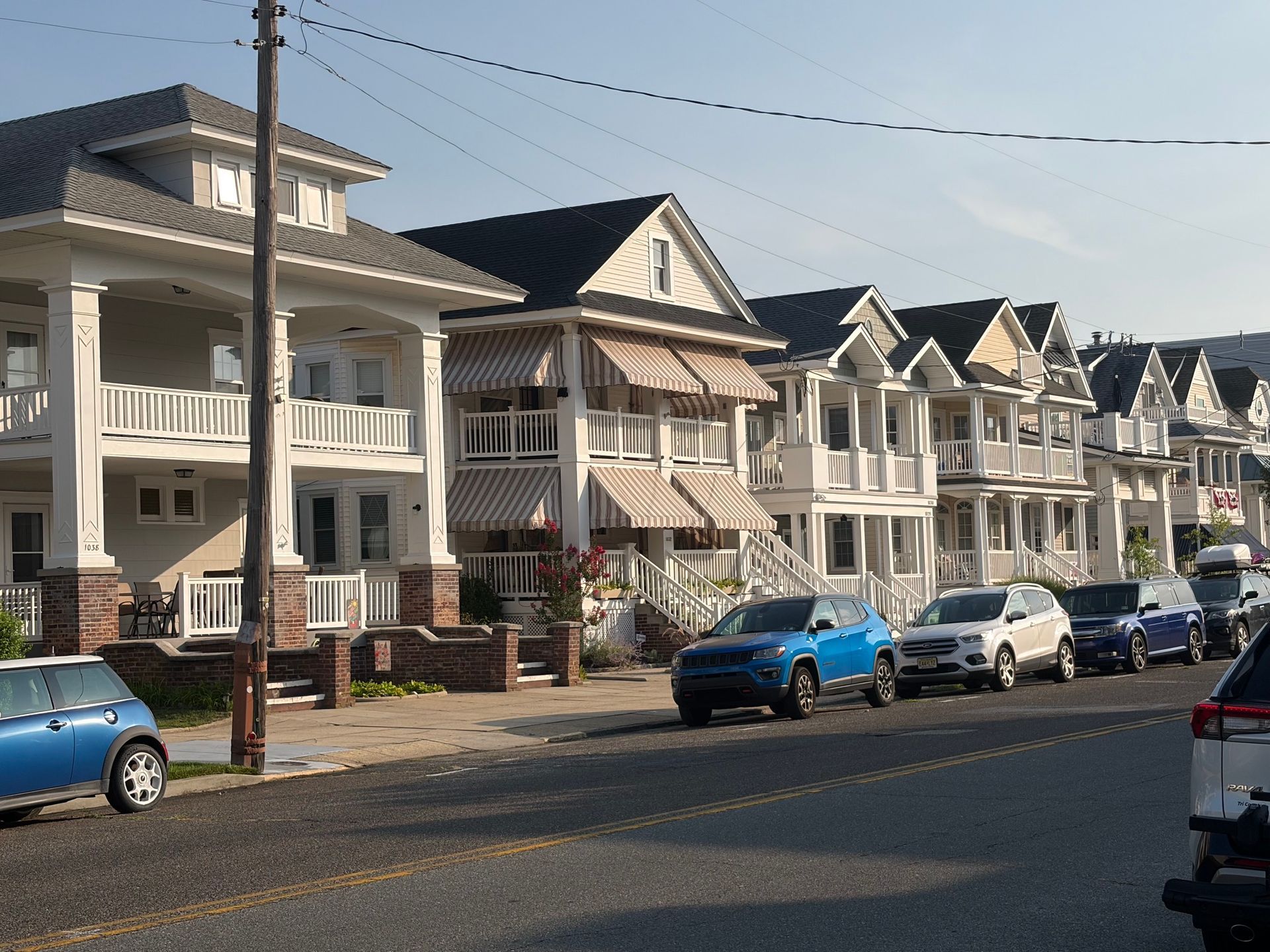 Row of white seaside houses with parked cars on a sunny street