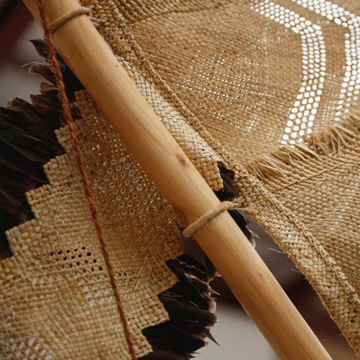 Close-up of woven straw fabric and bamboo poles on a rustic parasol or shade structure