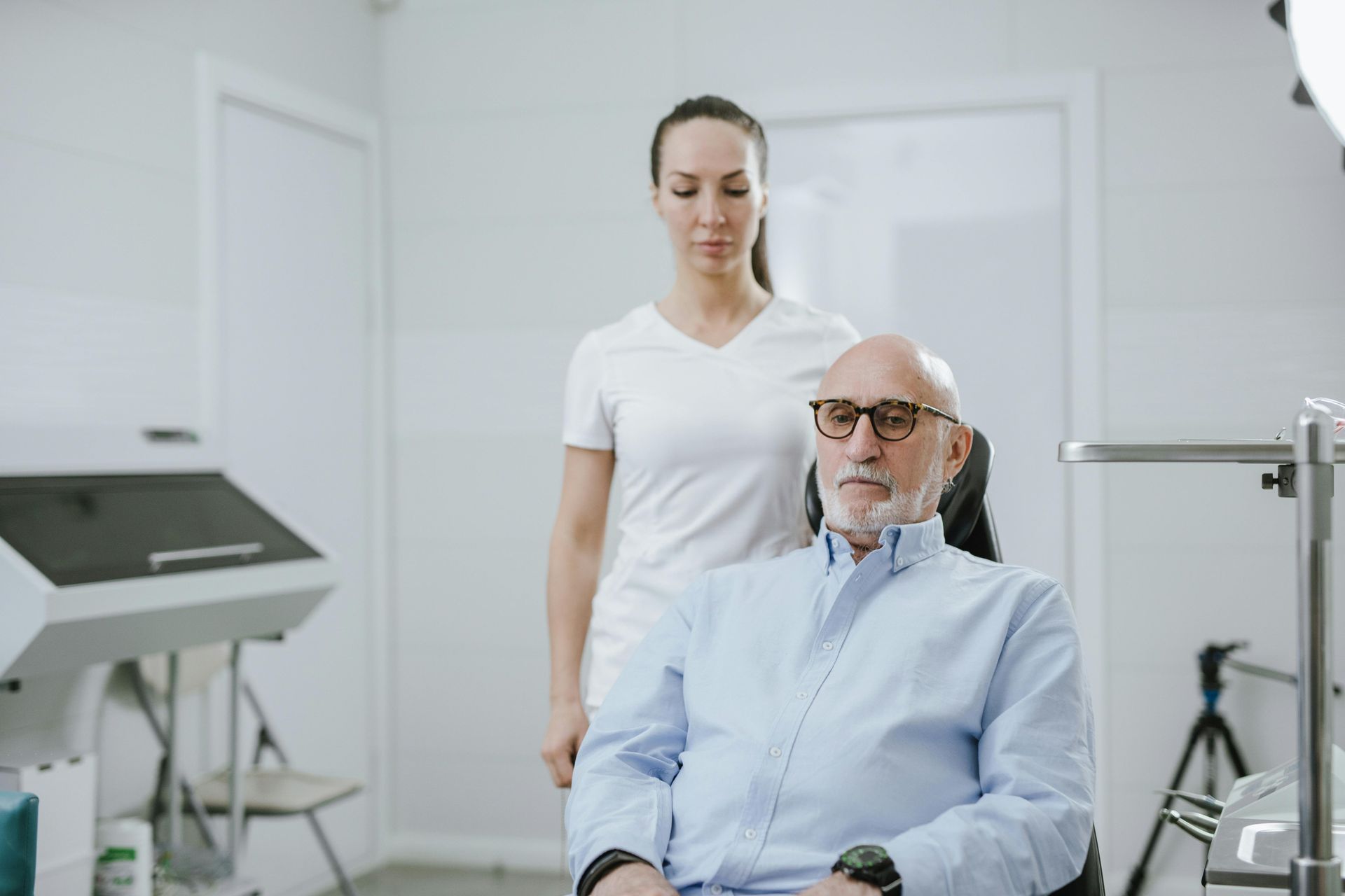 A man is sitting in a chair with a nurse standing behind him.