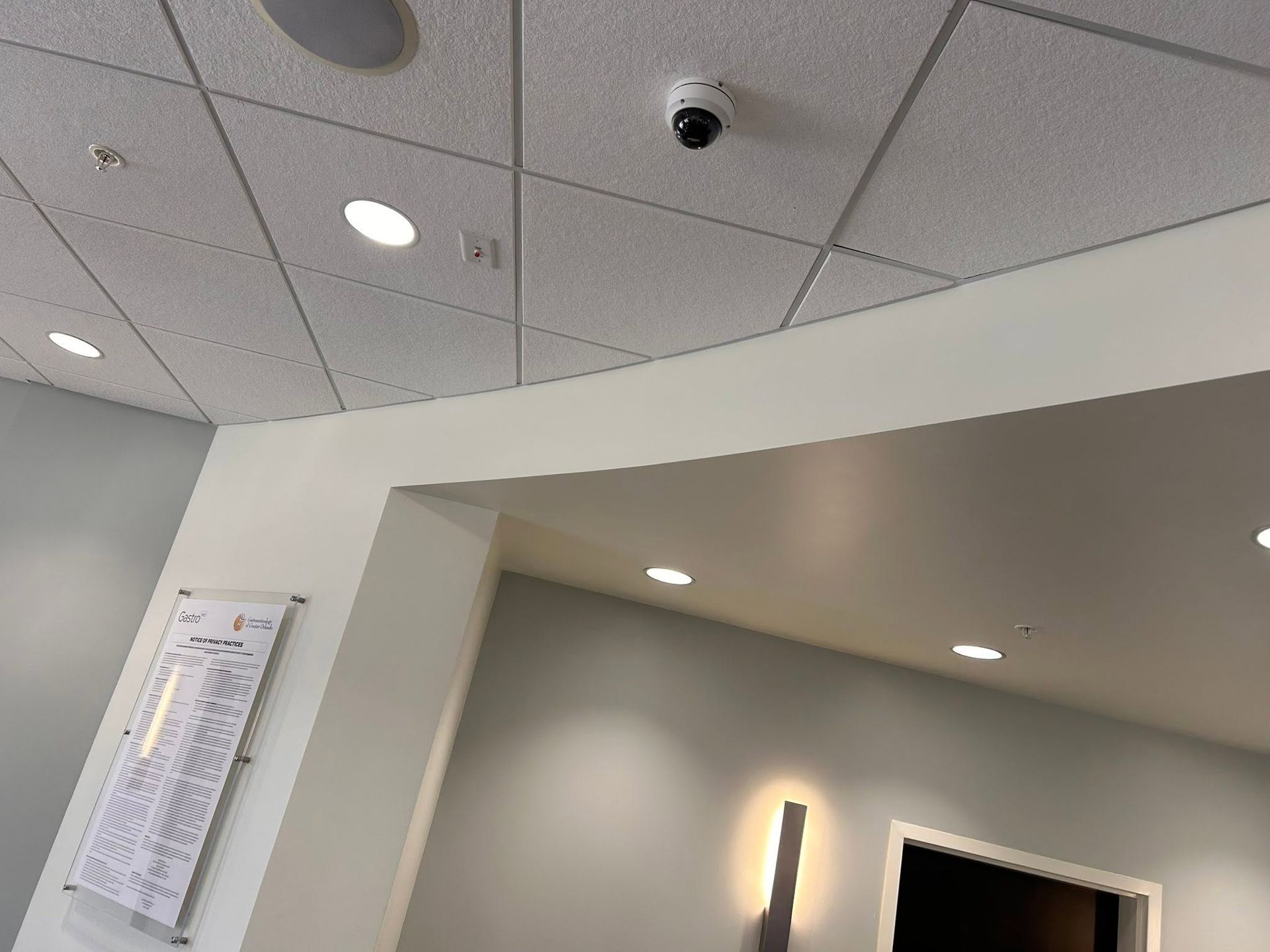 Office ceiling with recessed lights, smoke detector, and a wall opening below