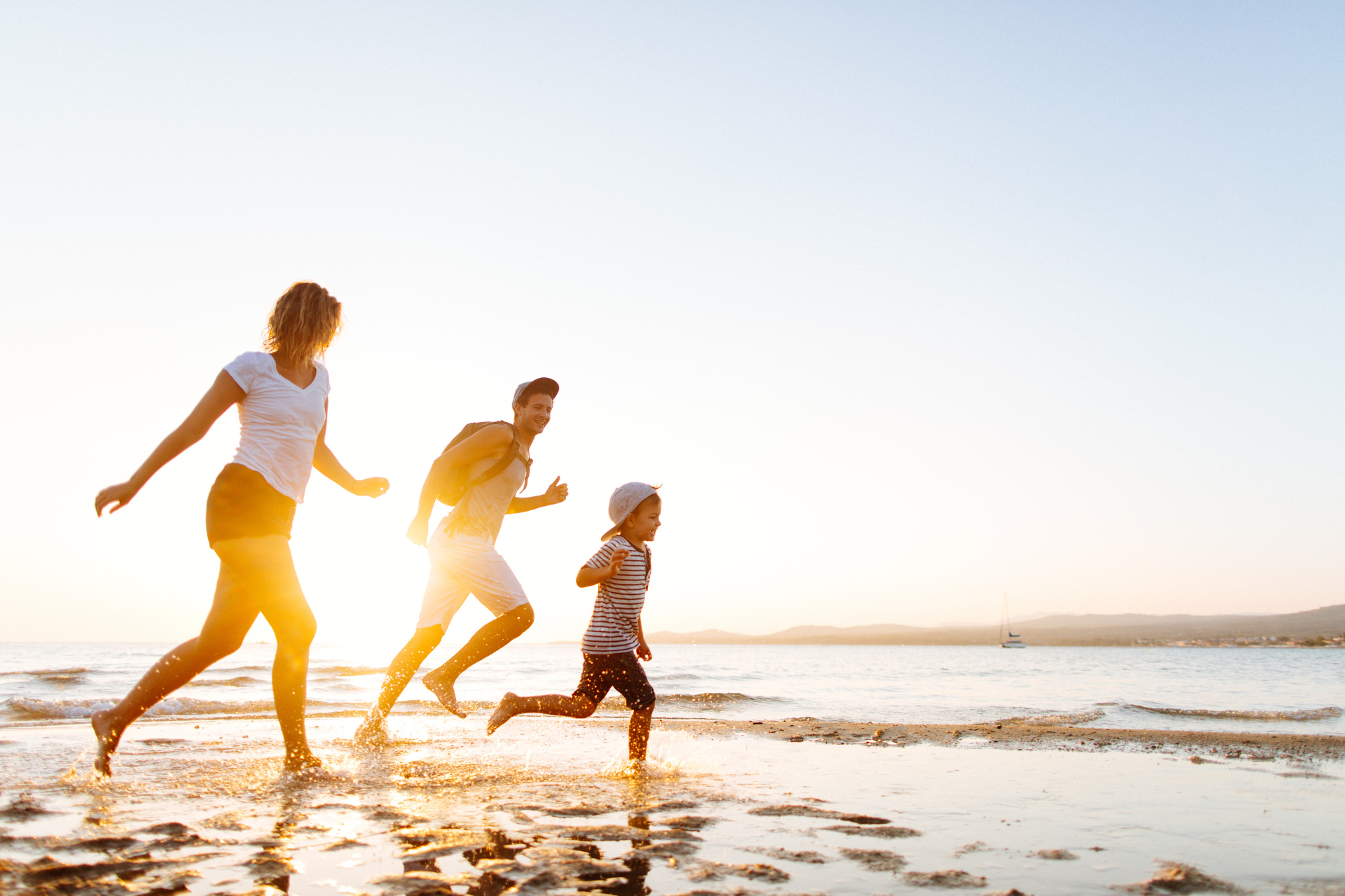 People running along a beach at sunset, with sunlight reflecting on the water