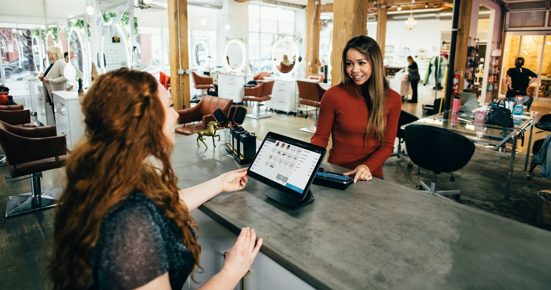 Two women talking at a cafe table, with a tablet open between them.