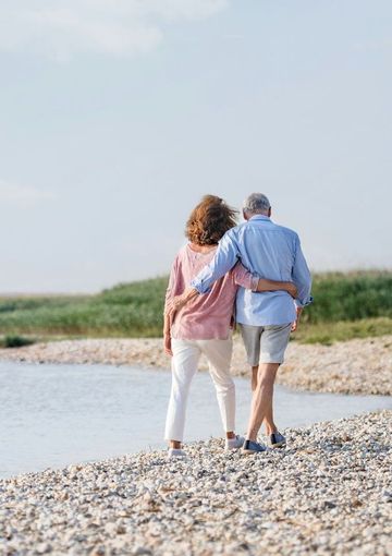 a man and a woman are walking on a rocky beach .