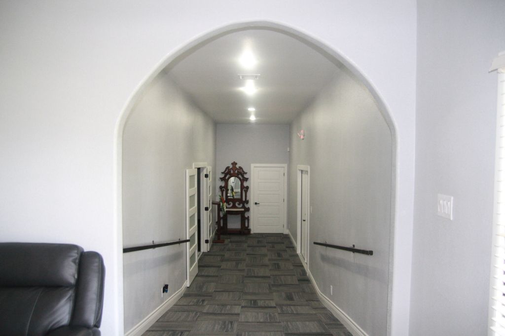 A long hallway with a black couch in the middle of it.