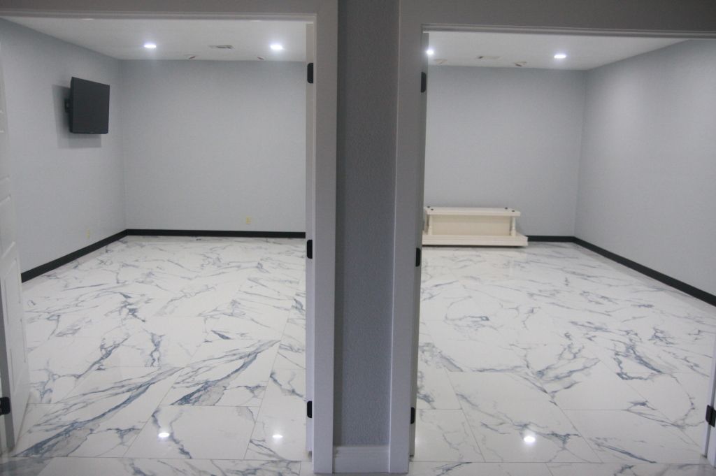 An empty room with marble floors and a television on the wall.