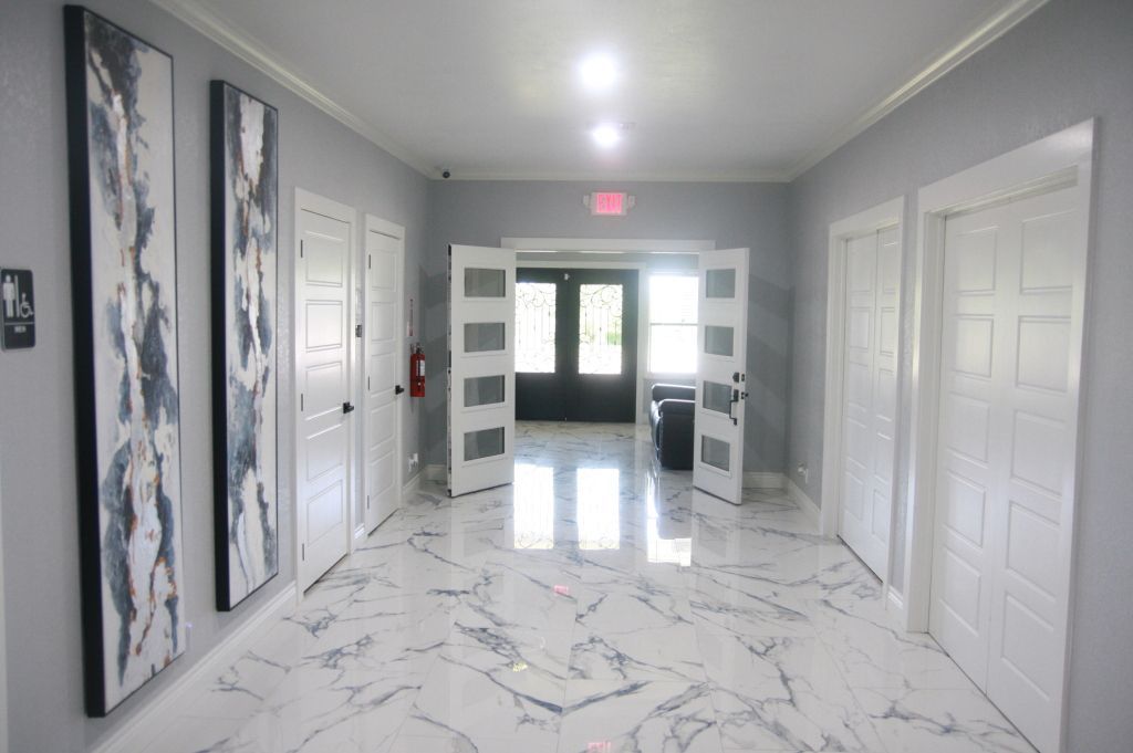 A long hallway with marble floors and white doors