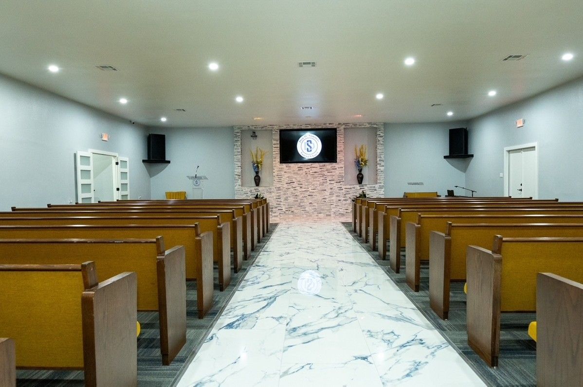 A church with rows of wooden benches and a marble floor.