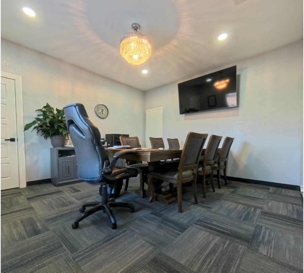 A conference room with a table and chairs and a television on the wall.