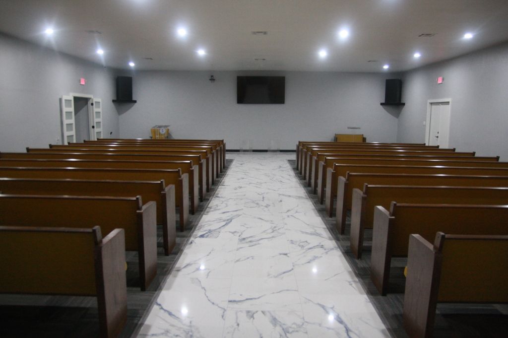 A church with rows of wooden benches and a marble floor.