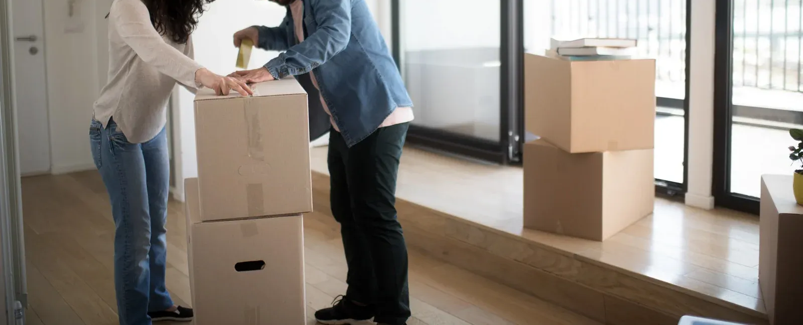 Two people packing cardboard boxes indoors.