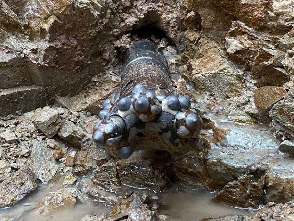 A large metal object is sitting in the middle of a rocky area.