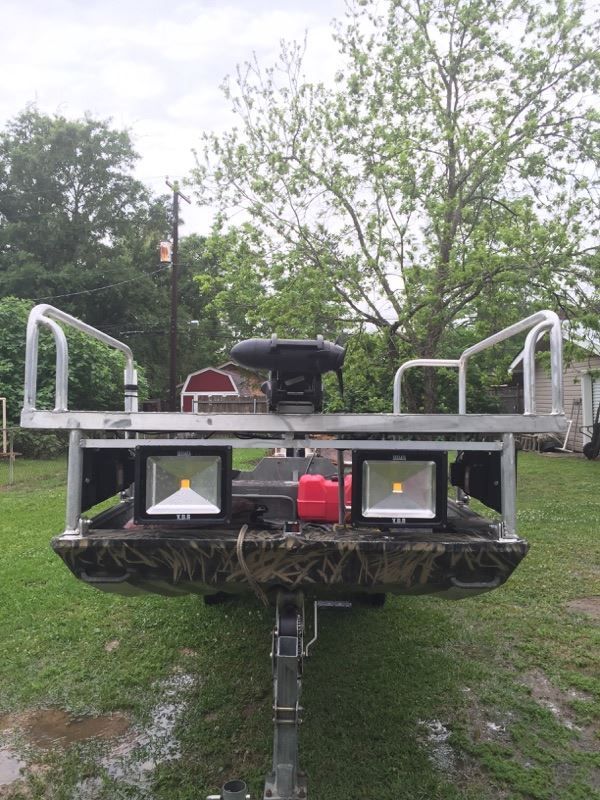 Duck hunting boat with floodlights, aluminum rails, camouflaged paint, and a trailer.