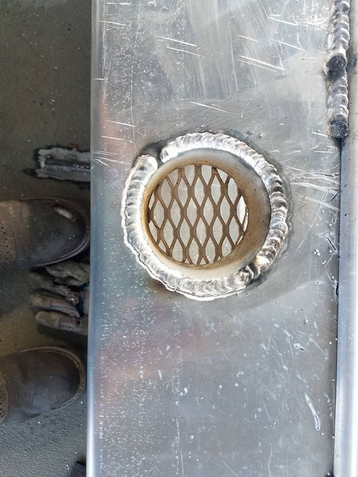 Metal plate with welded, round grill. A person's shoes are in the bottom left corner.