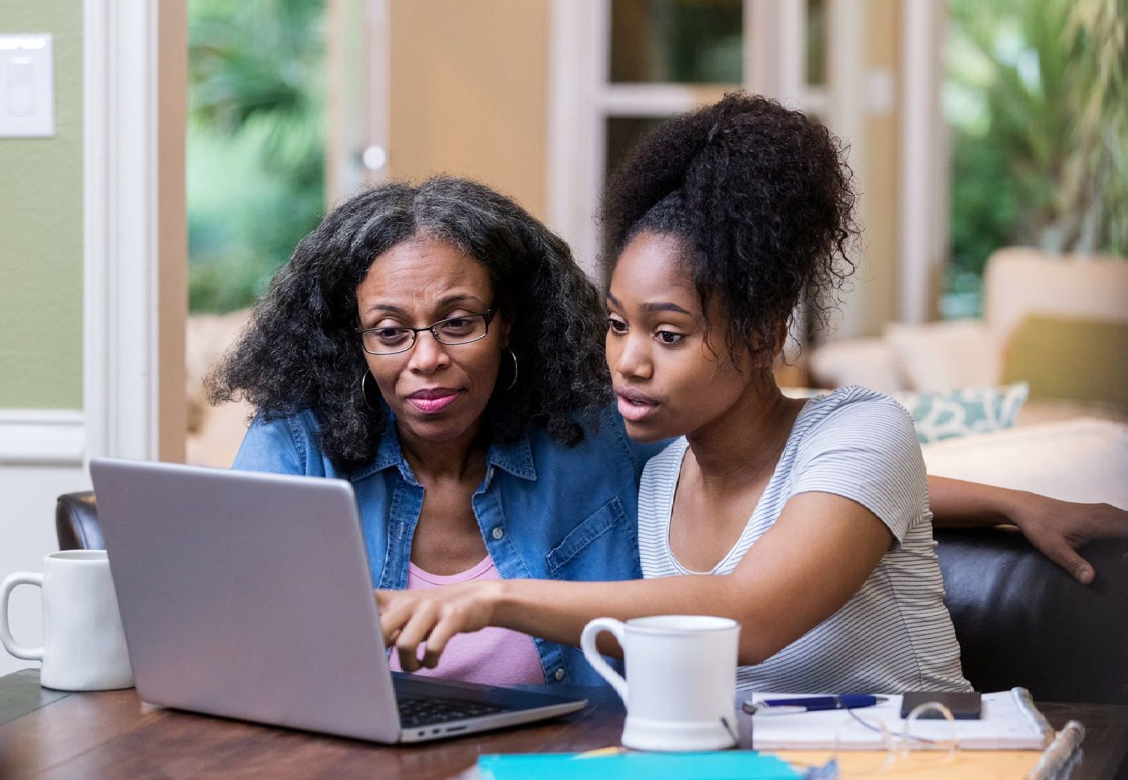 A mother and daughter are looking at a laptop computer.