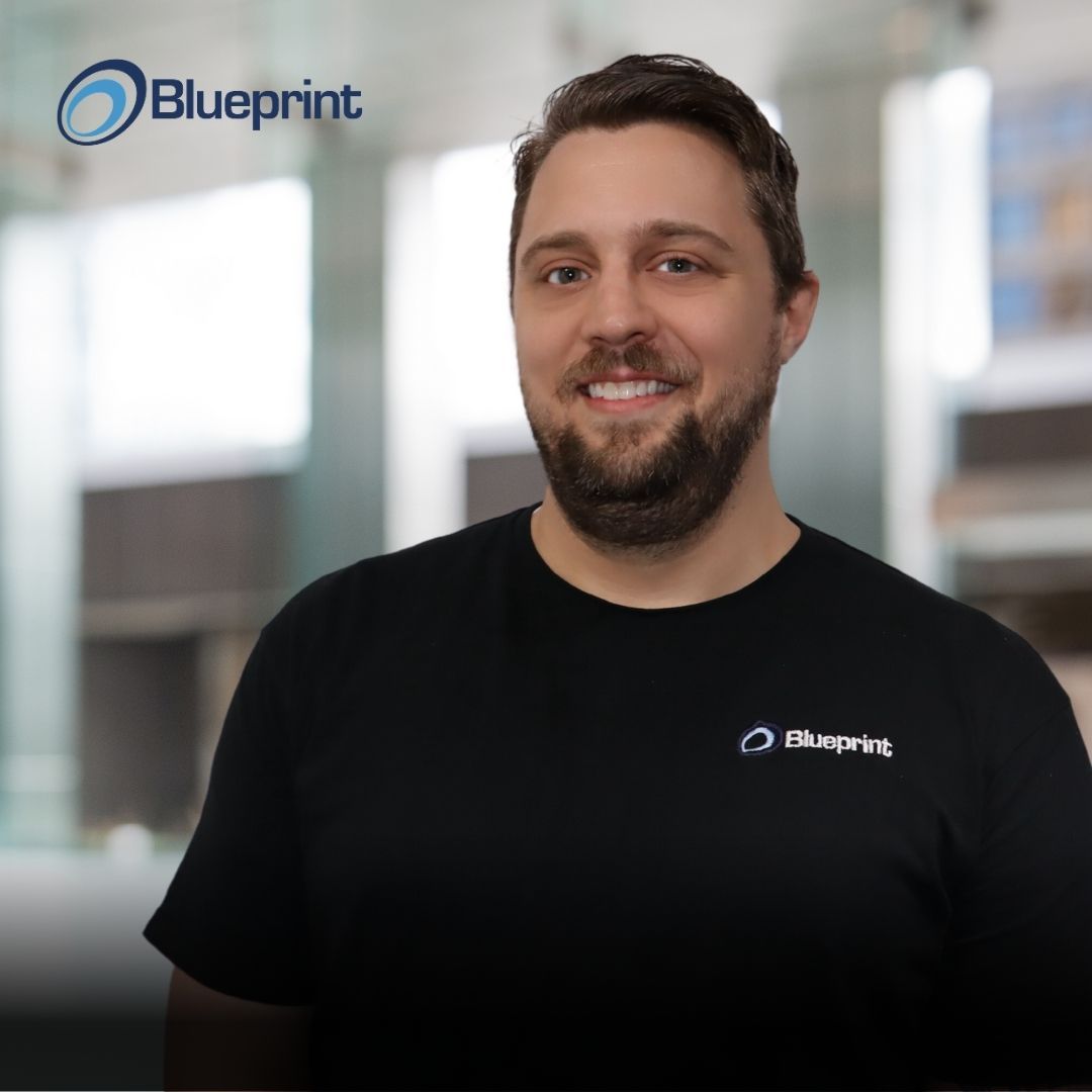 A man with a beard is wearing a black shirt that says blueprint