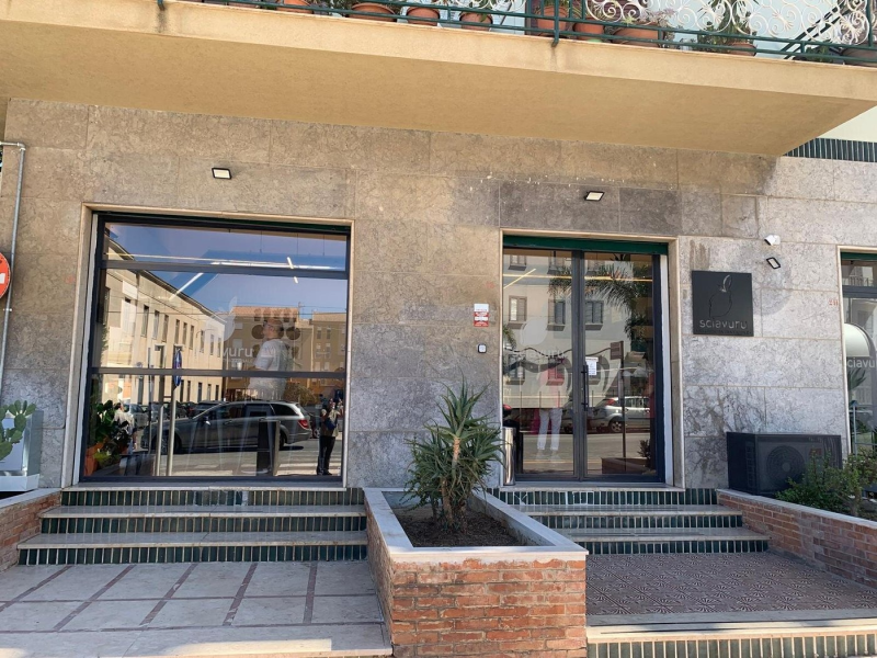 Esterno di un negozio con porte in vetro e facciata in granito. Una scalinata conduce all'ingresso.
