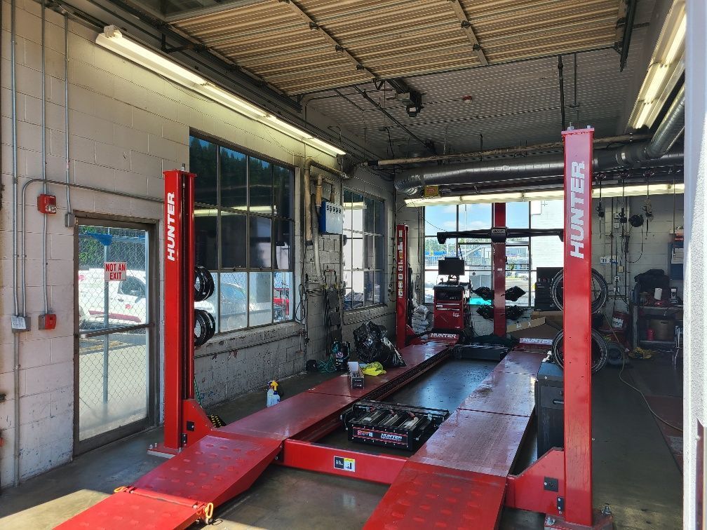 Inside a car repair shop, red Hunter lift, windows, tools, and equipment visible.