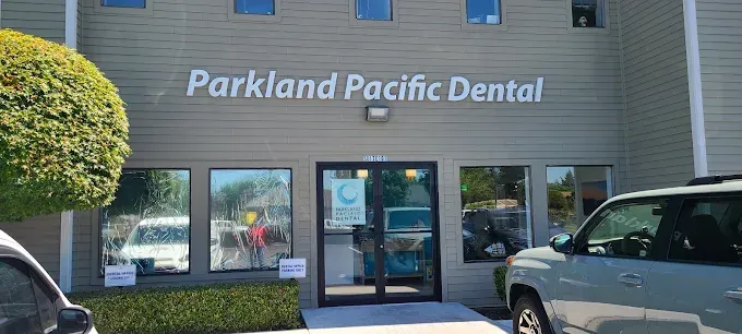 Exterior of Parkland Pacific Dental office building. Grey facade, glass windows, and sign.