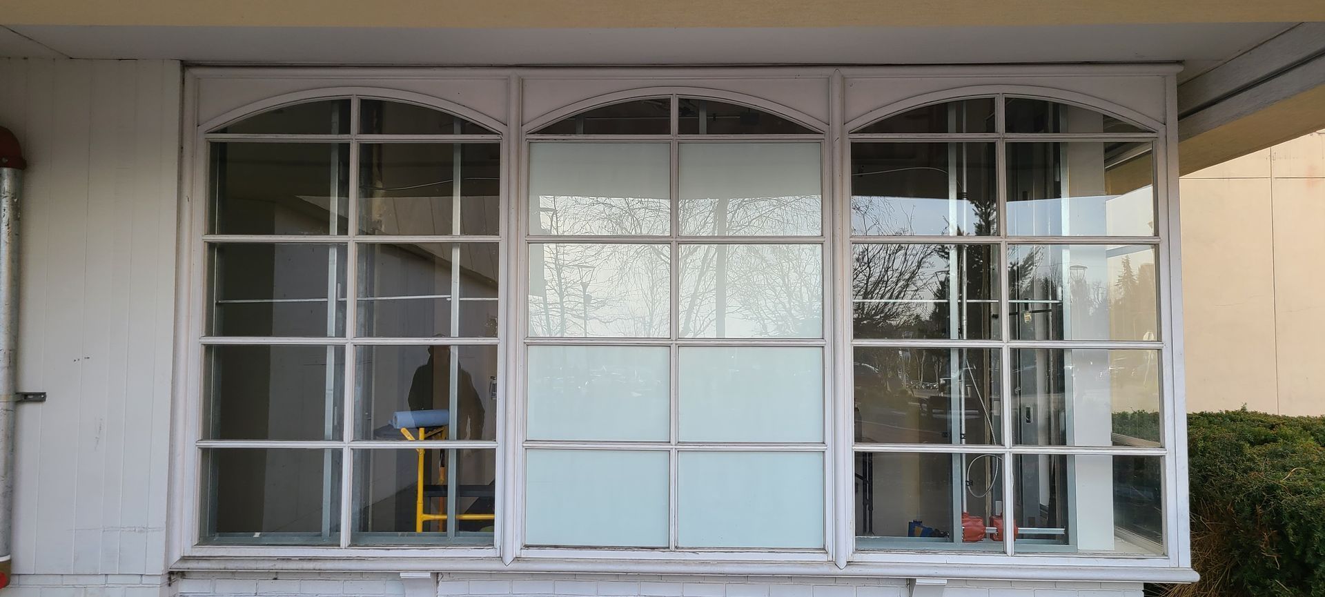 Three arched windows with white frames, a decorative top, and partial frosted glass; exterior.