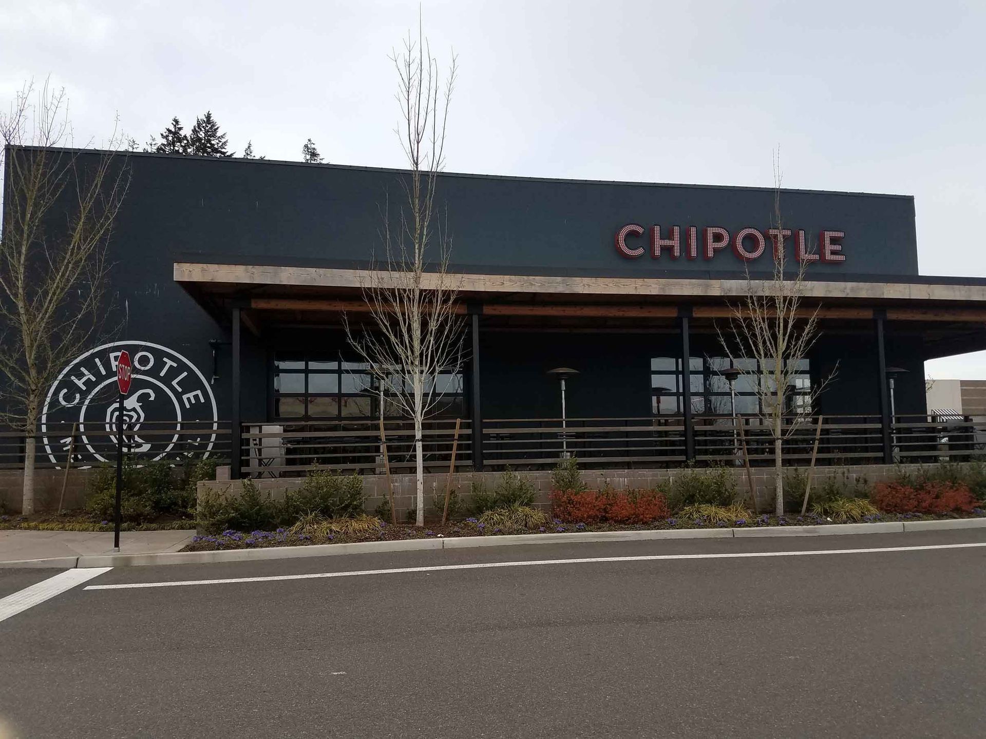 Chipotle restaurant exterior with a dark gray facade and a large logo on the side.