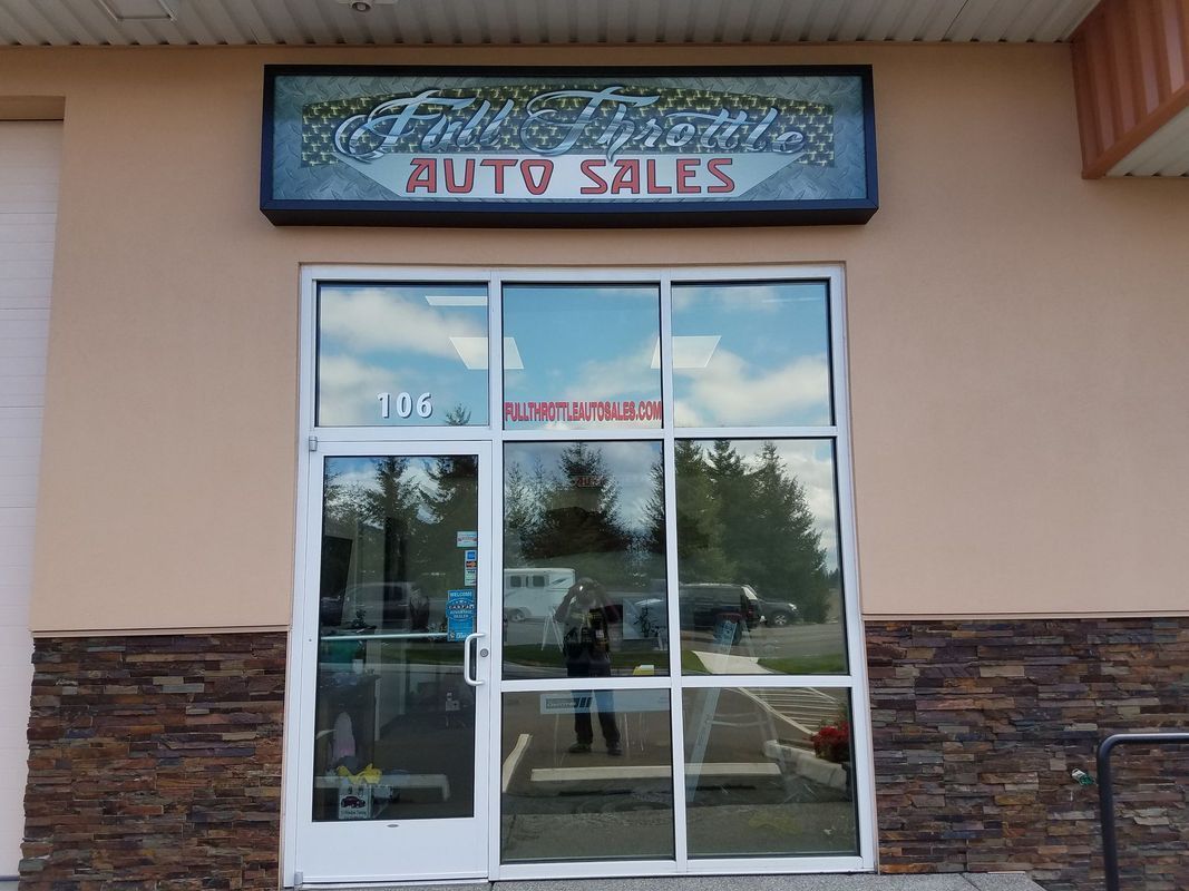 Auto sales business front entrance with sign, windows and door.