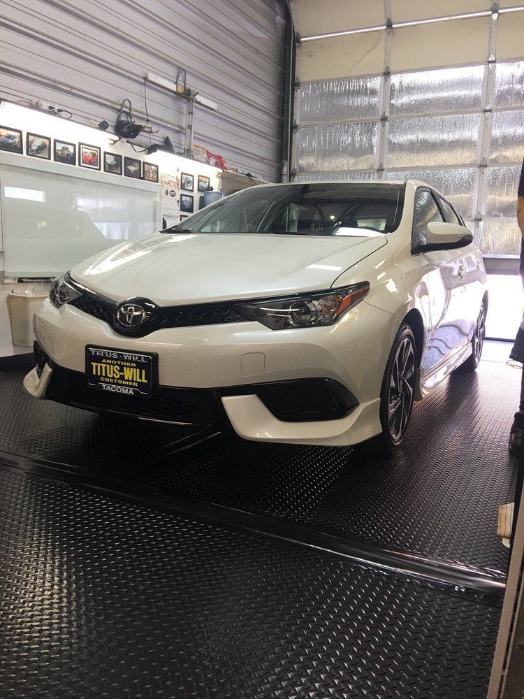 White Toyota Corolla in a garage, standing on a black patterned surface.