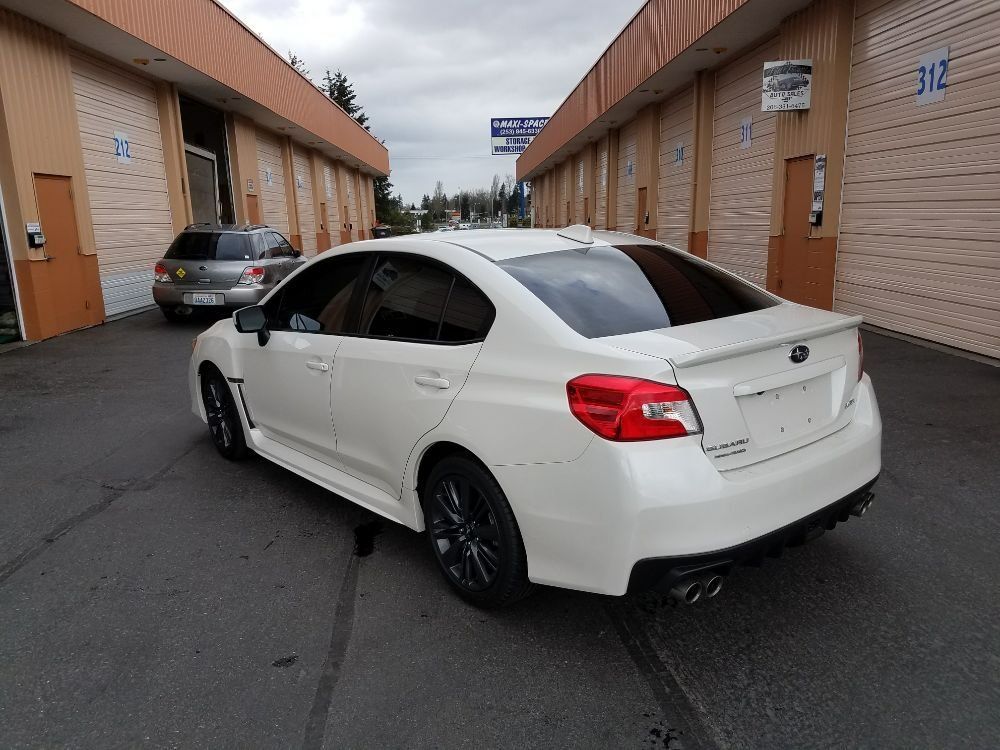 White Subaru WRX parked outside of a building with garage doors.