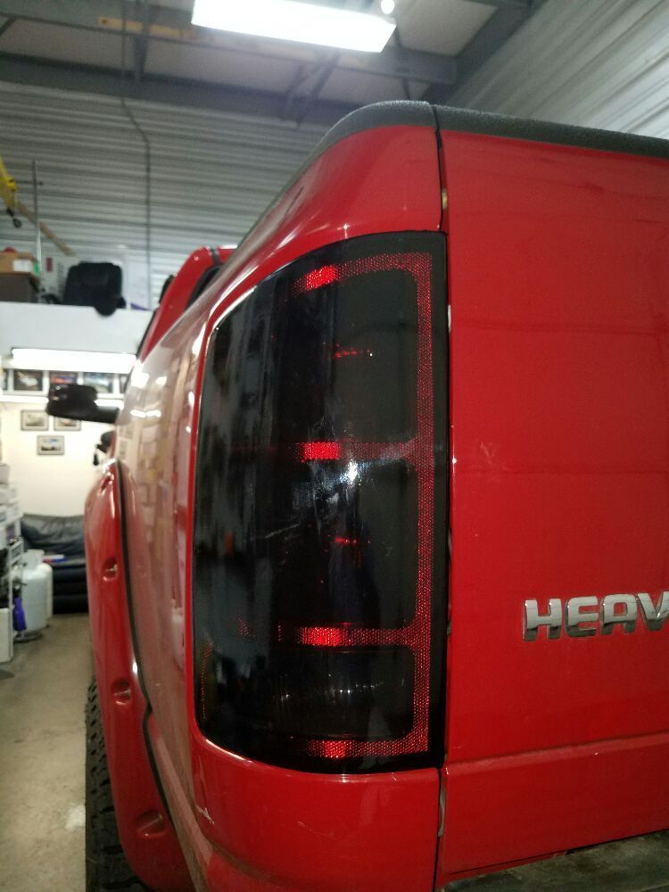 Red truck's taillight with black tinted lens. HEAVY DUTY is visible. Inside setting.