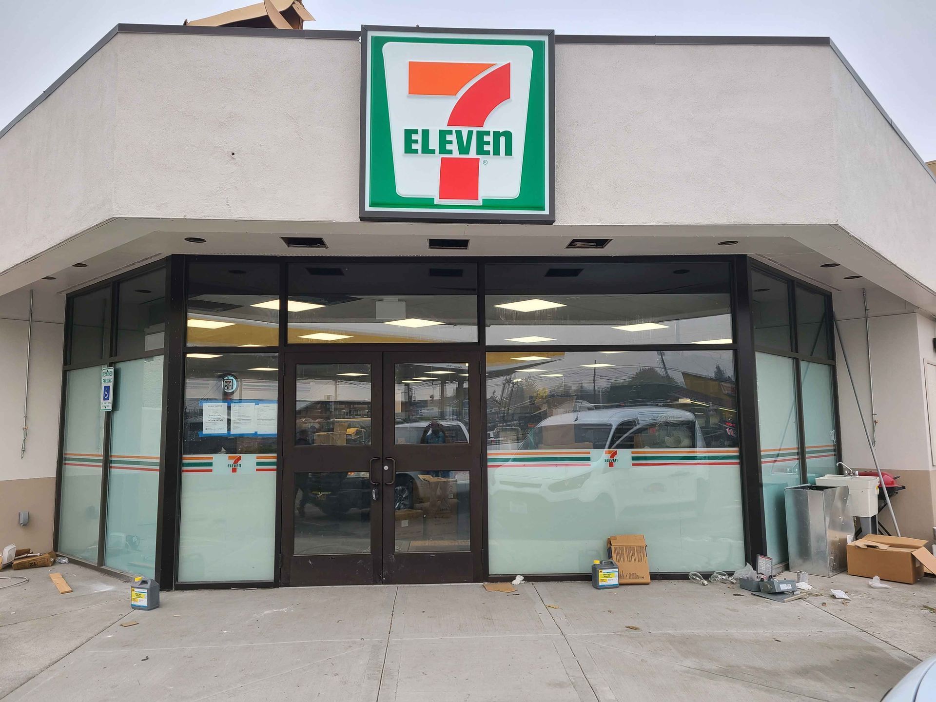 7-Eleven store front with boarded up windows, construction debris, and 7-Eleven logo.