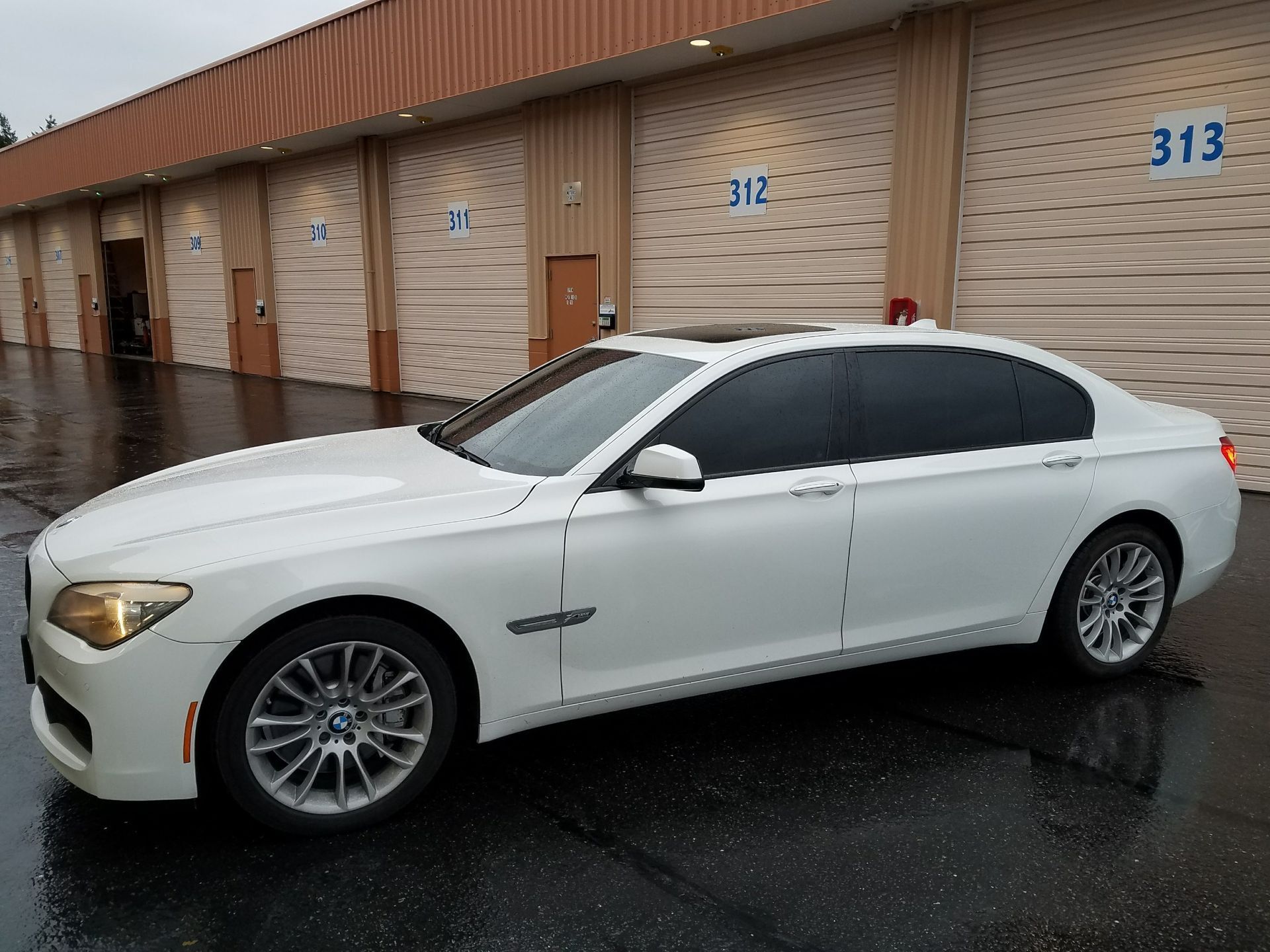 White BMW sedan parked in front of a row of storage units. It's a cloudy day.