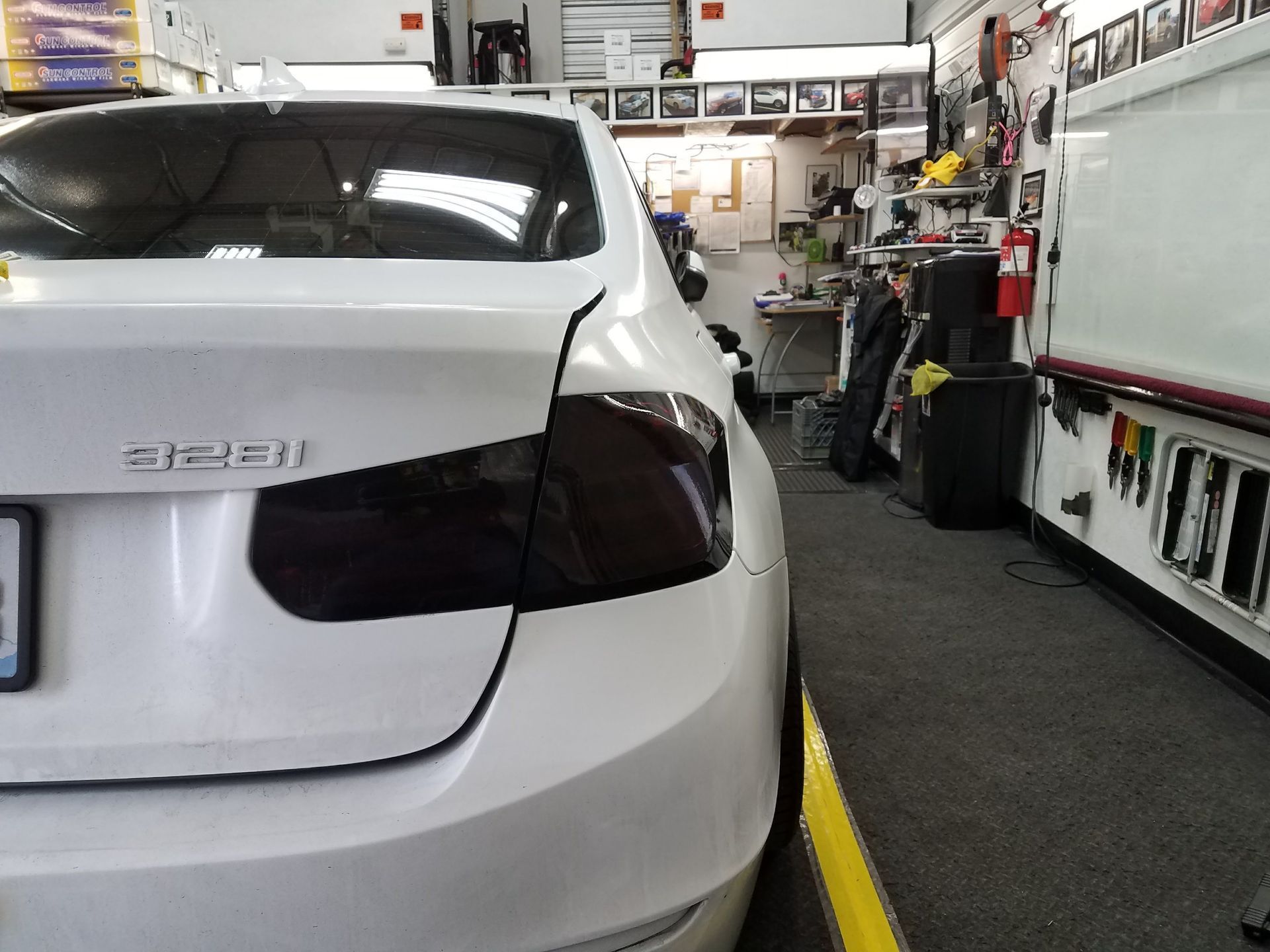 White BMW with tinted taillights in a shop, black trim on the rear.