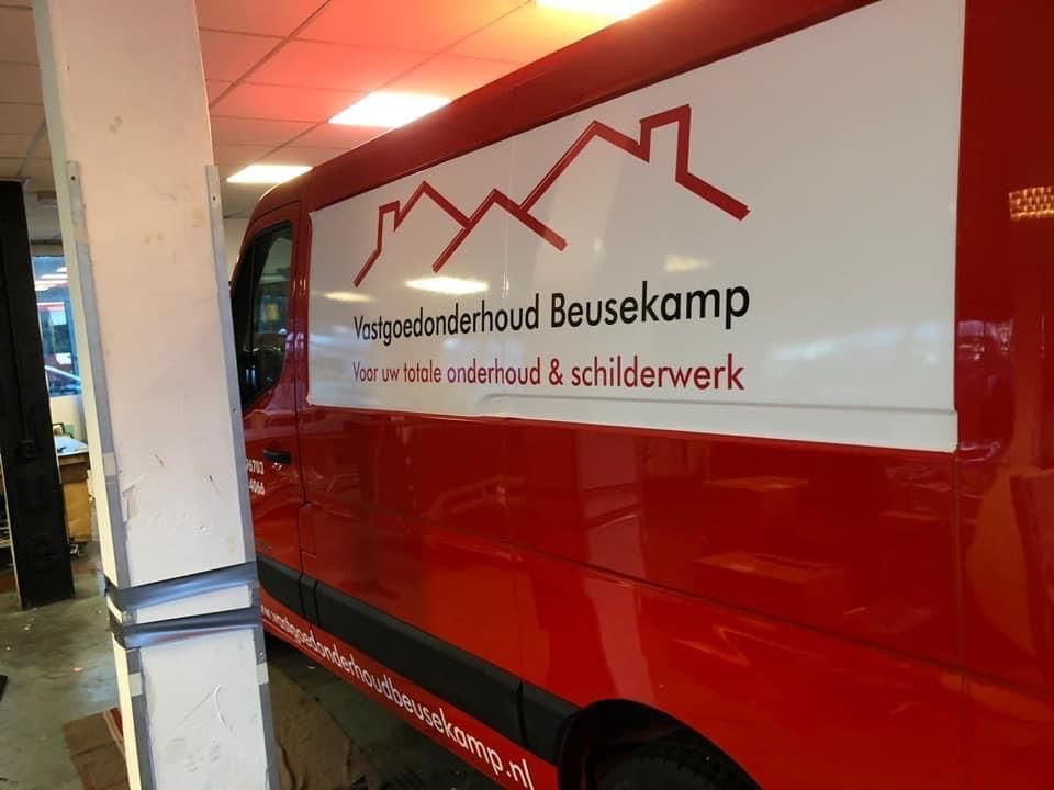 Een rode servicebus stond binnen geparkeerd, met daarop een witte afbeelding van het bedrijf