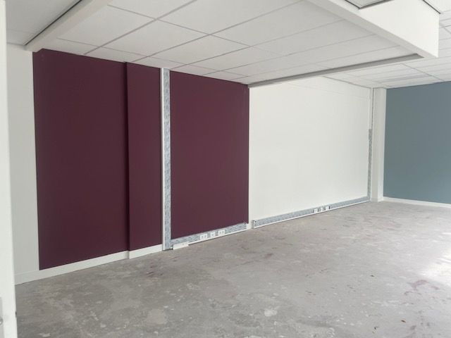 Een interieurfoto van een ruimte in aanbouw met paars, wit en turquoise geverfde muren en onafgewerkte betonnen vloeren.