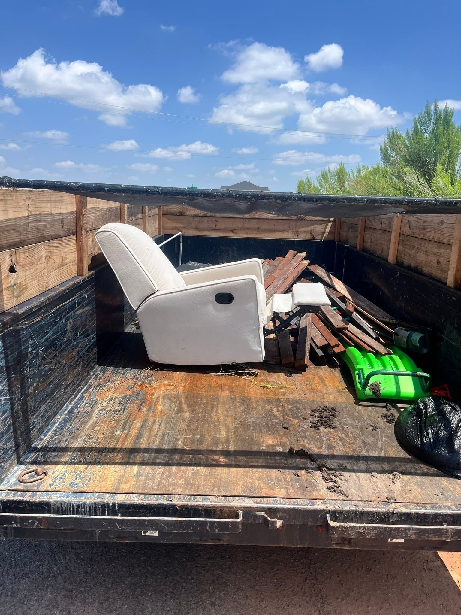 Dump trailer with scrap metal and debris under a blue sky.