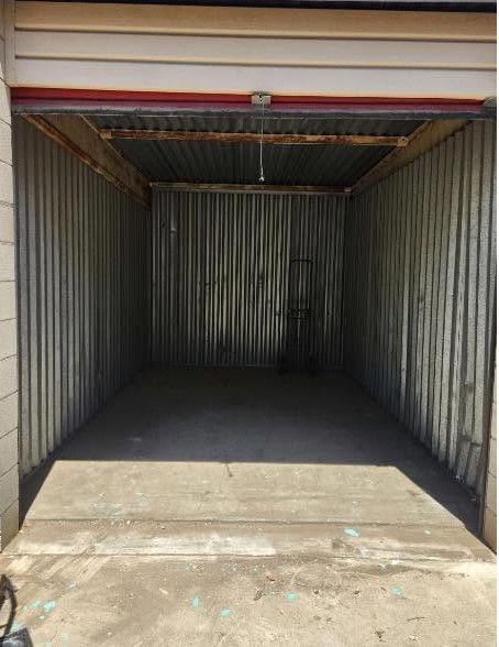 Empty shipping container interior with corrugated metal walls and open doorway in front
