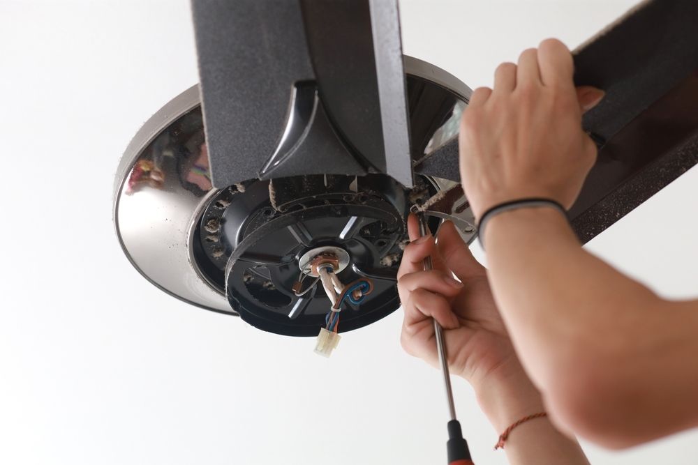 A Person Uses a Screwdriver to Perform Maintenance on A Ceiling Fan Motor — AC/DC Electrical, Air Conditioning & Refrigeration In Gatton, QLD