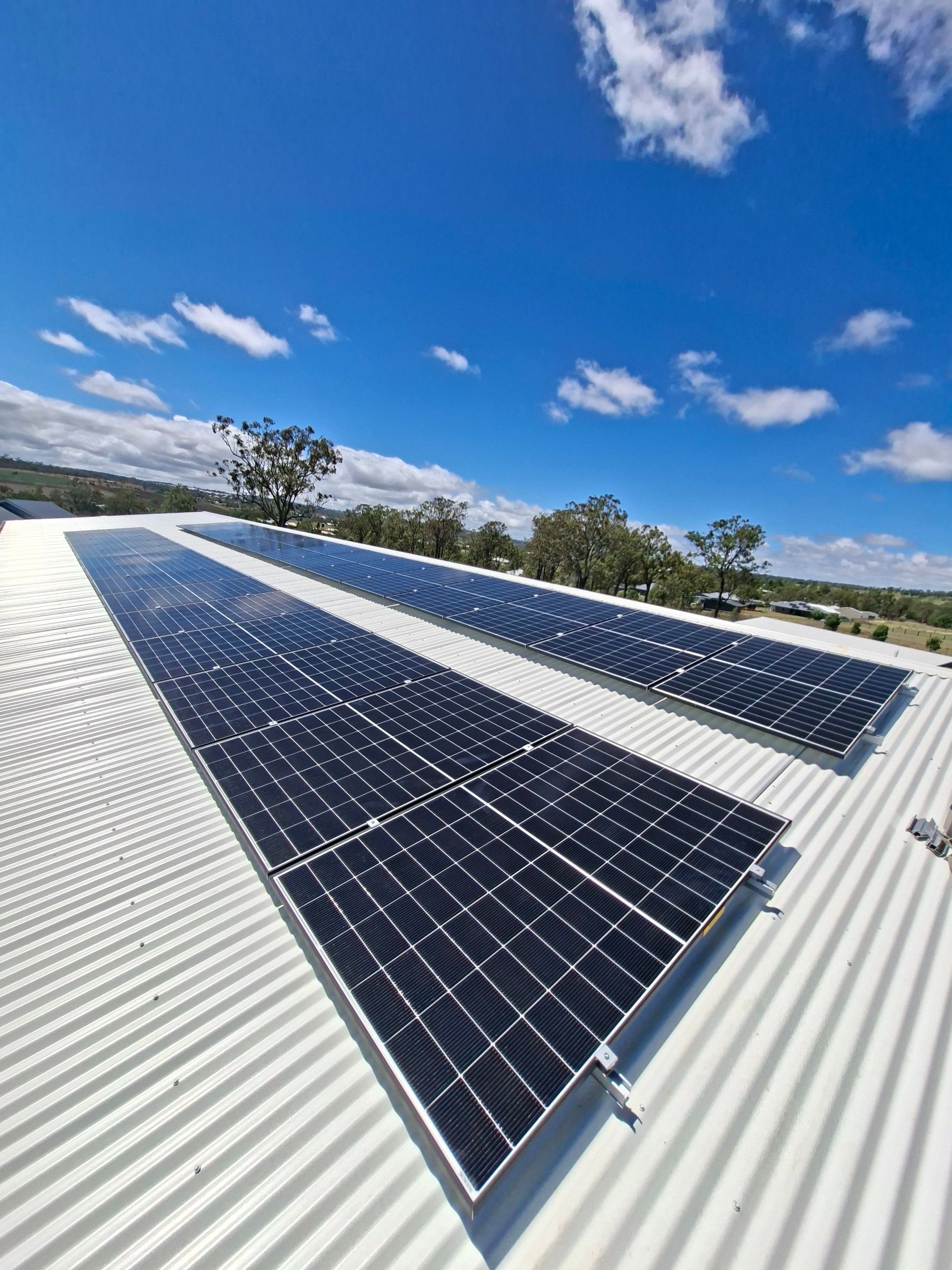 Solar panels on a corrugated rooftop under a bright blue sky