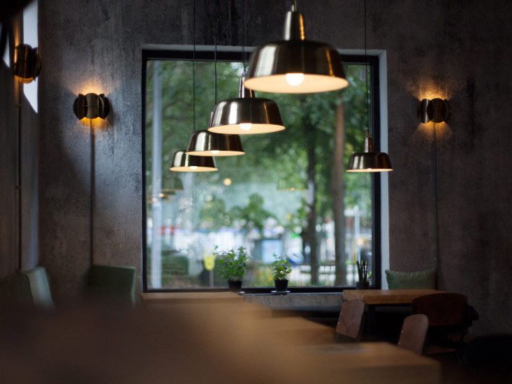 A Cozy, Dim Restaurant Interior with Hanging Metal Pendant Lights — AC/DC Electrical, Air Conditioning & Refrigeration In Zilzie, QLD