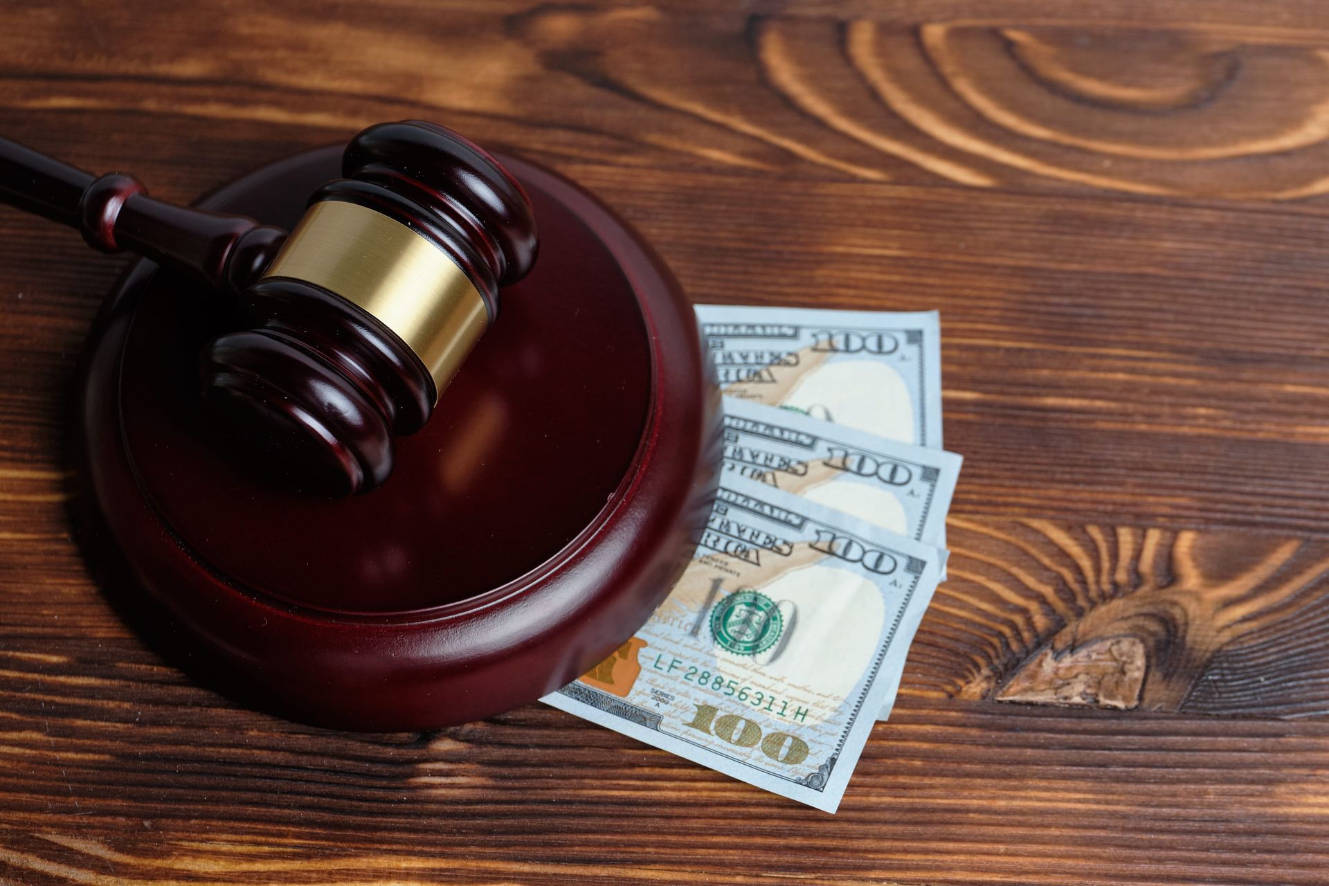 Judge’s gavel on a wooden surface beside U.S. dollar bills