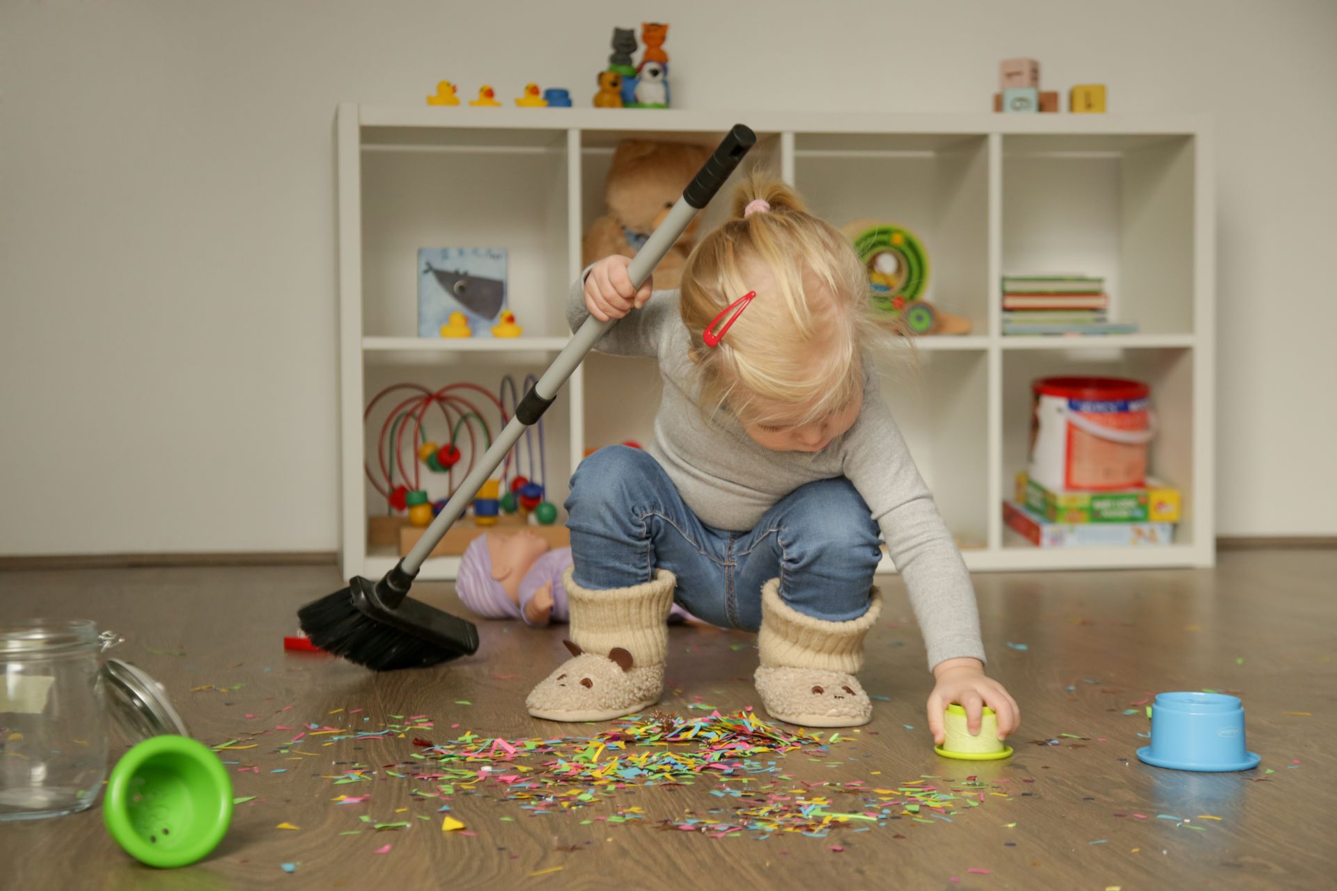 A little girl is cleaning the floor with a broom.
