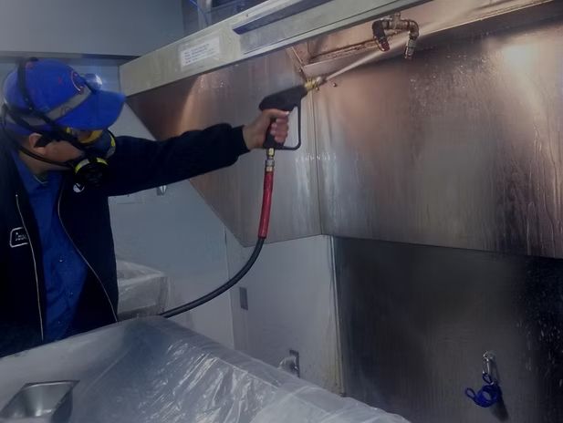 A worker is cleaning the stainless steel kitchen hood A worker is cleaning the stainless steel kitchen hood