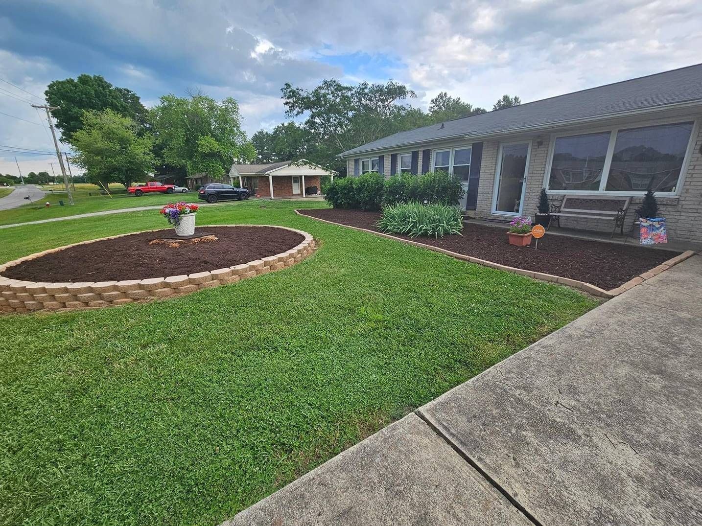 A house with a lush green lawn and a circular garden in front of it.