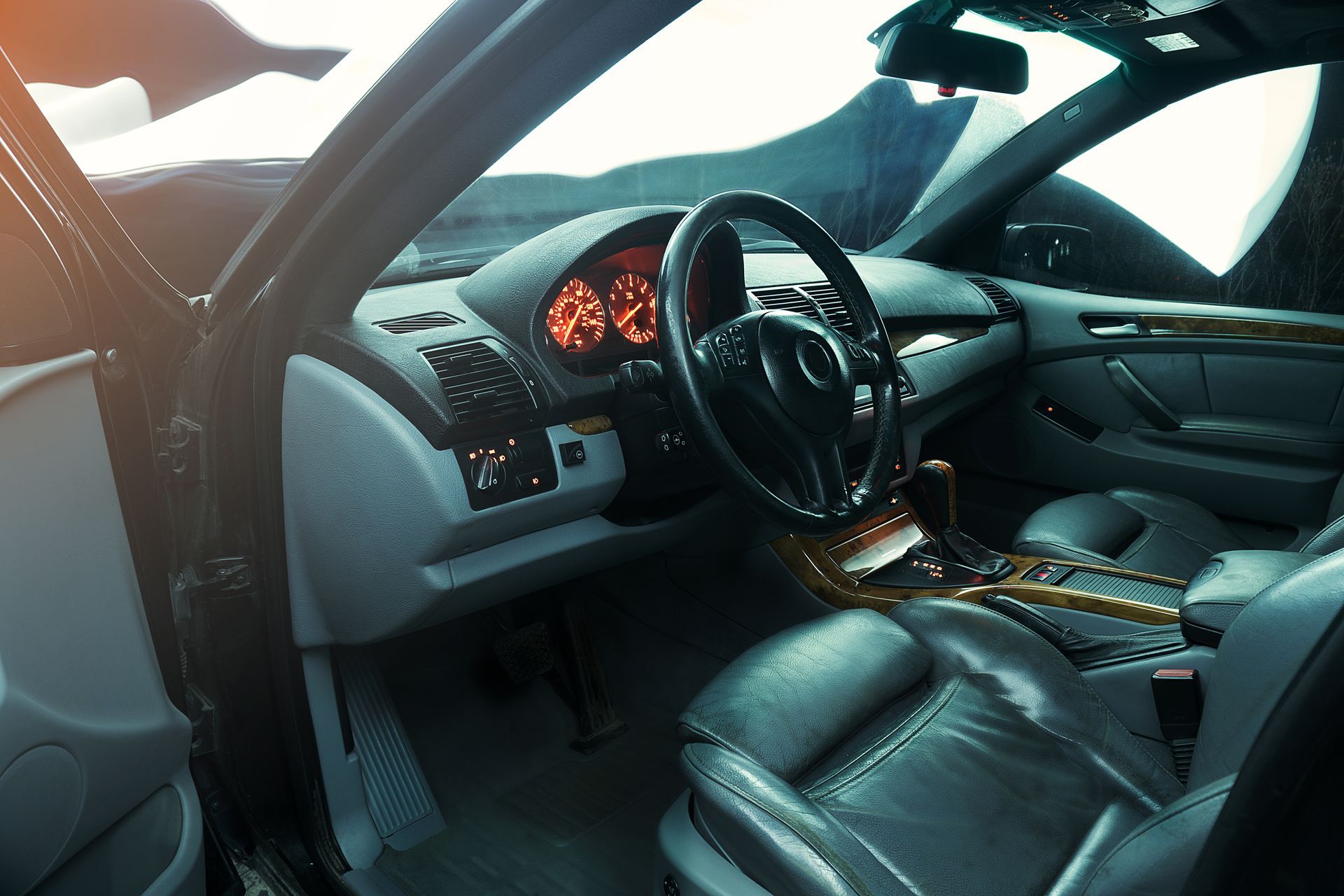 Black leather car interior with illuminated dashboard and open driver’s door