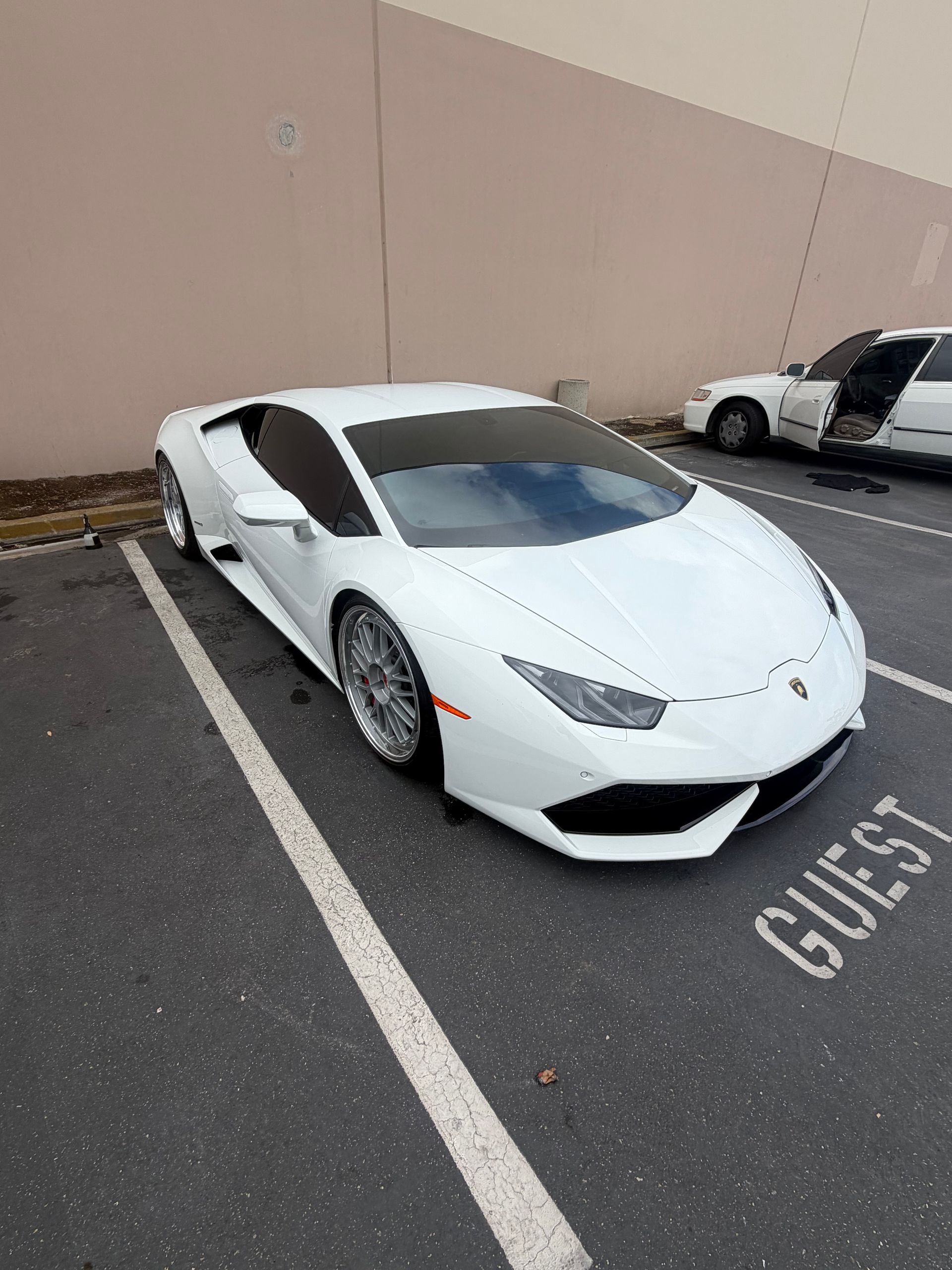Hand wiping a black sports car’s hood in a dark garage