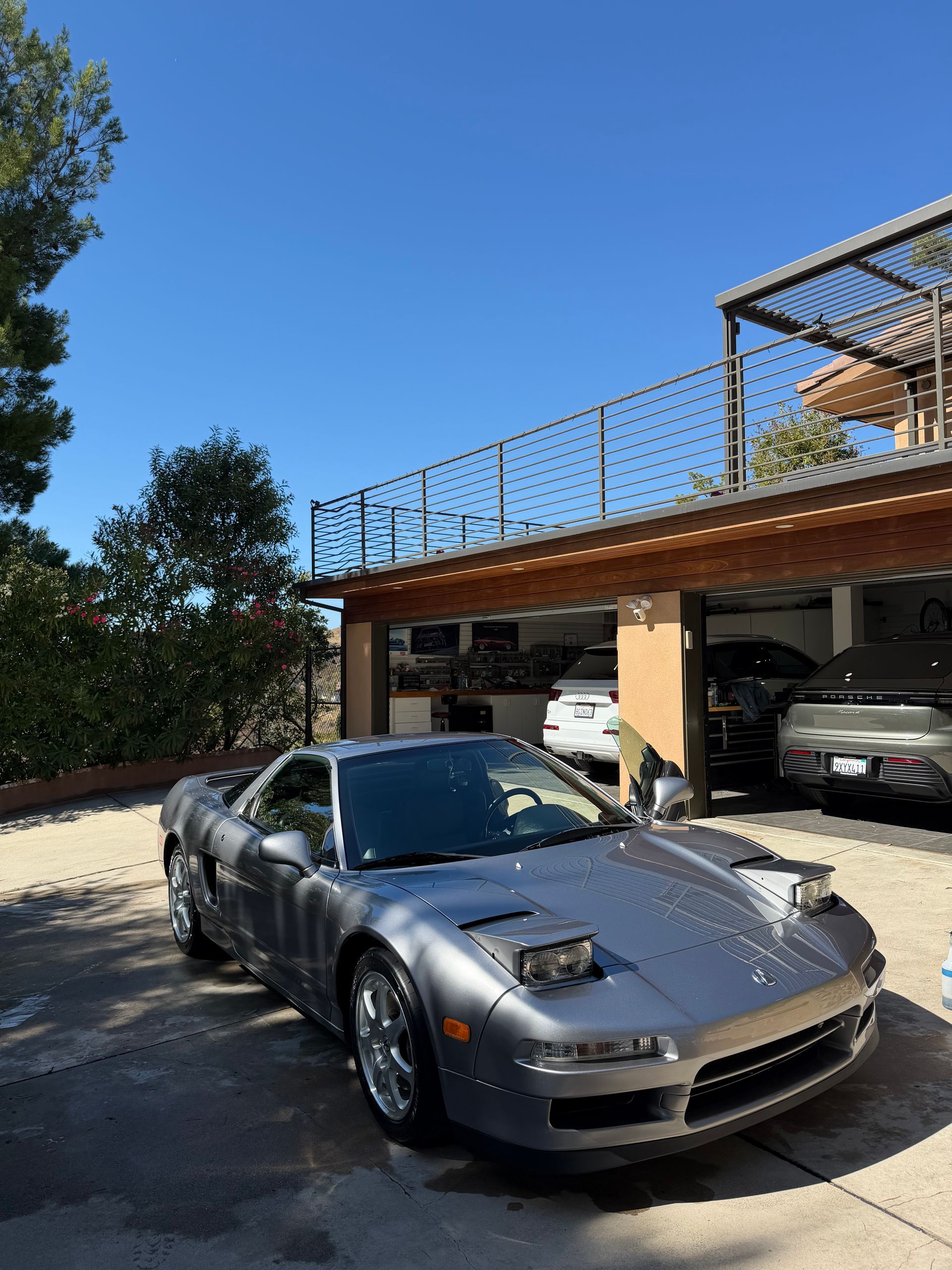 Gloved hand polishing a black sports car in a garage, with a motorcycle in the background