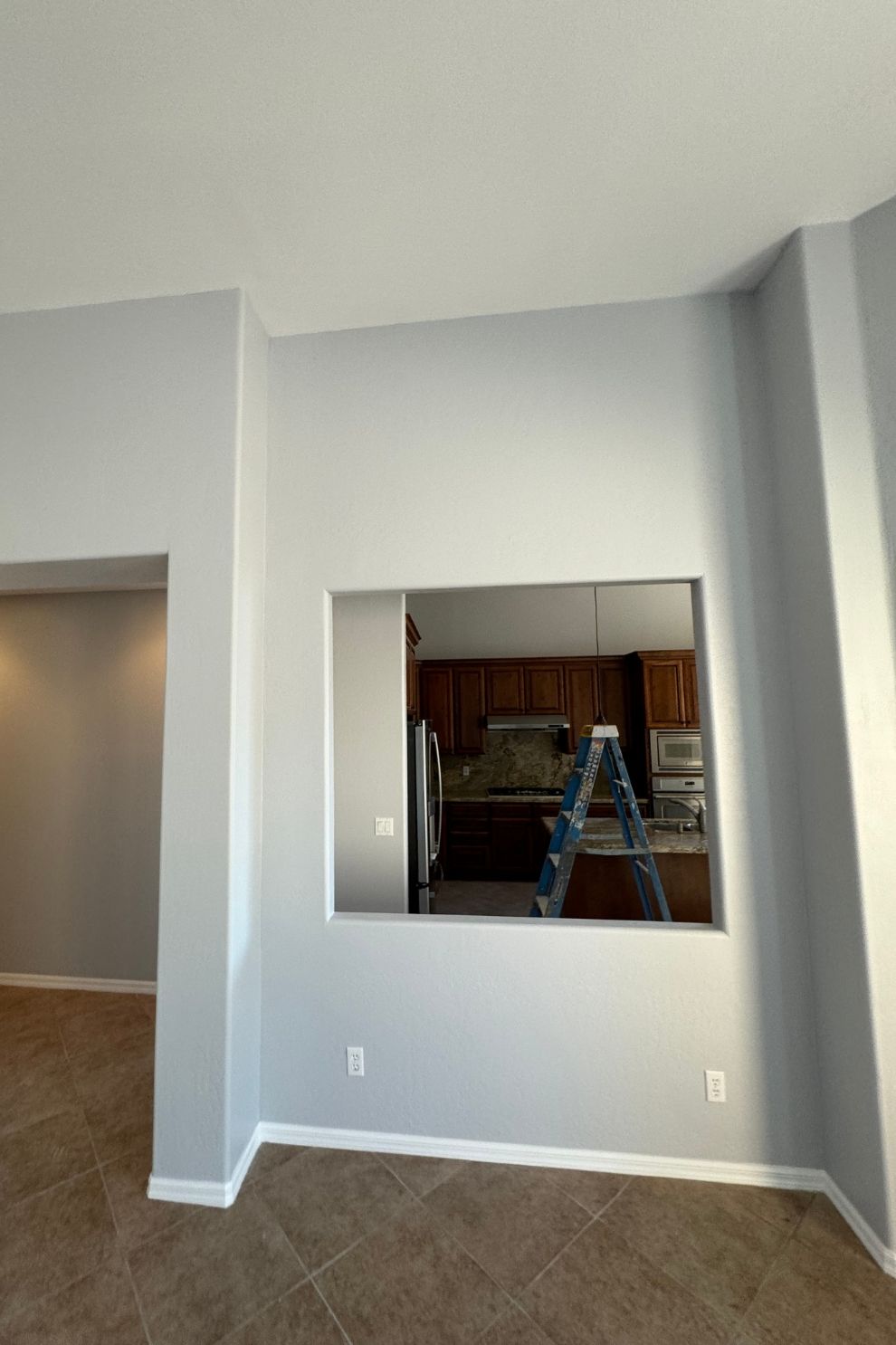 There is a window in the wall that looks out to the kitchen.