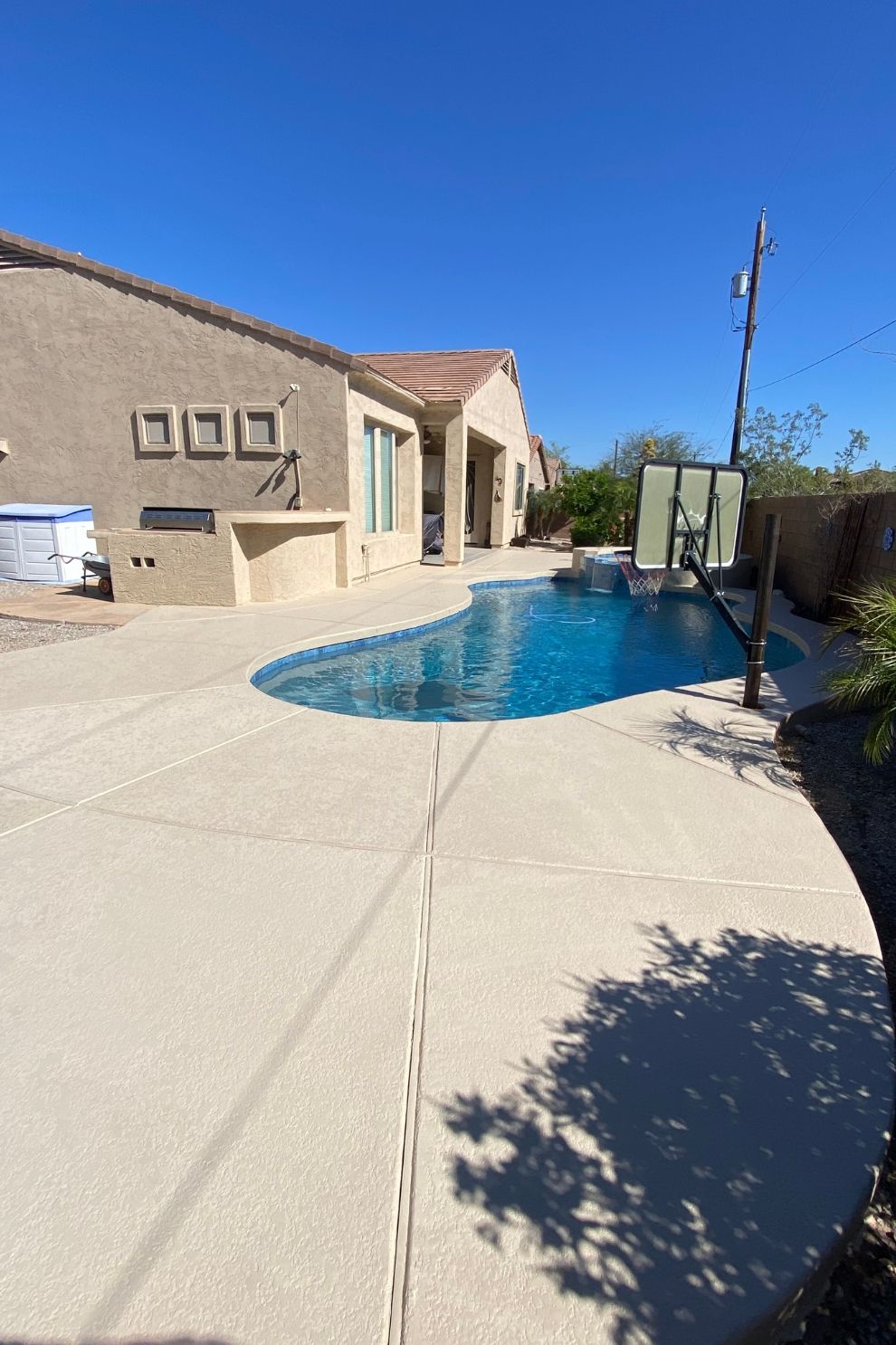 A large swimming pool is in the backyard of a house.