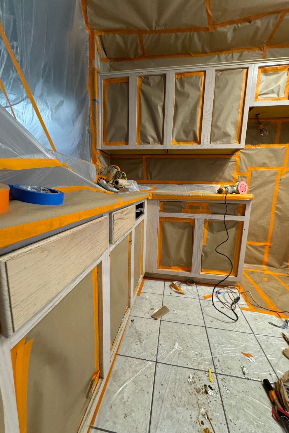 A kitchen is being painted and covered in plastic.