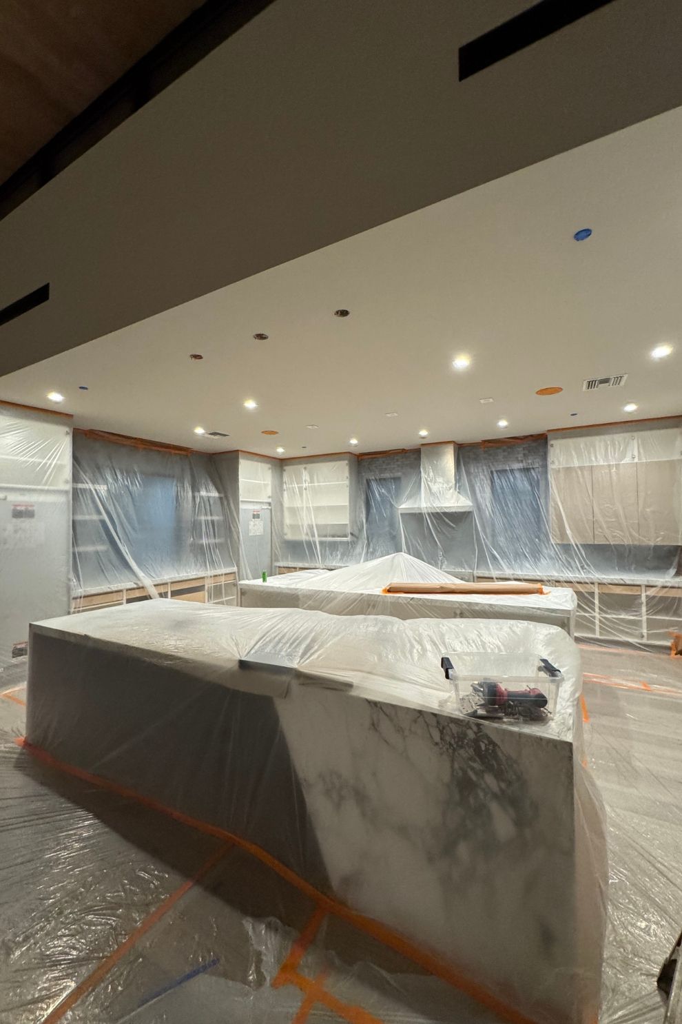 A kitchen is being remodeled and covered in plastic wrap.
