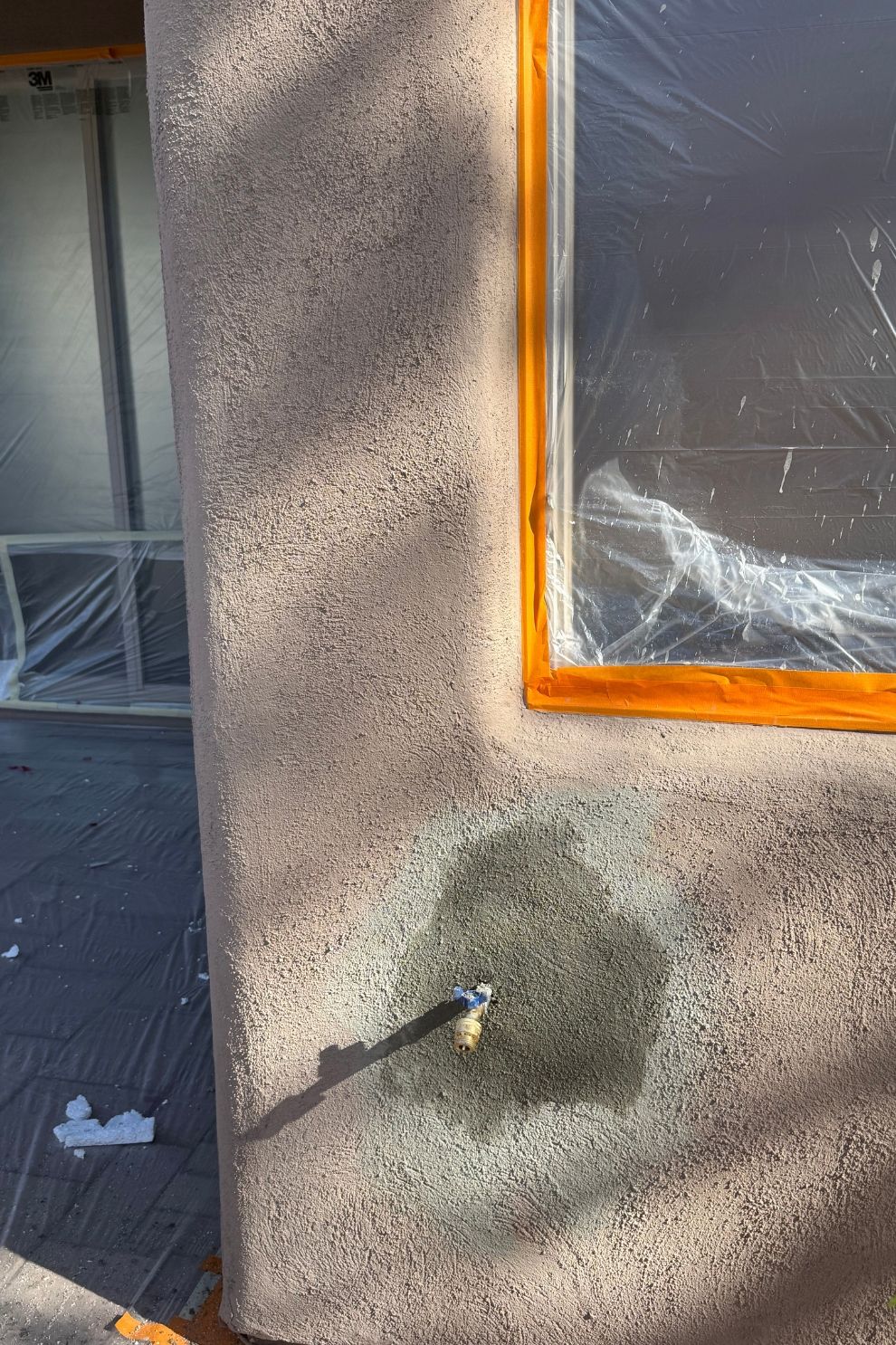 A close up of a wall with a window and a faucet on it.